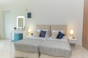 Ein Doppelbett mit zwei Nachttischen, ein Beistelltisch, ein Schreibtisch mit Stuhl, ein Spiegel und ein Kleiderschrank.
