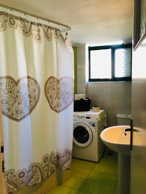 Ein Badezimmer mit Waschmaschine, Spüle und Fenster.