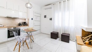 Eine moderne Küche mit Essbereich, Kamin und großem Fenster mit Vorhängen.