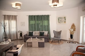 Ein modernes Wohnzimmer mit einer Couch, Sesseln, einem Couchtisch und einem Essbereich.