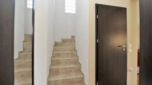 Eine Treppe führt zu einer dunklen Holztür, oberhalb davon befindet sich ein kleines Fenster.