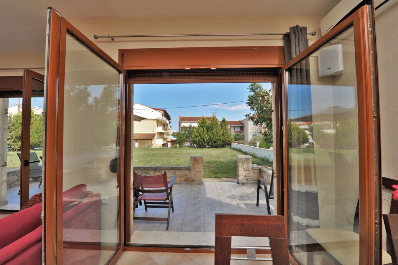 A room with a sliding glass door leading to an outdoor patio area with a chair and a table.