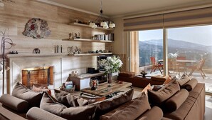 Een moderne woonkamer met een open haard, een bank, een bijzettafeltje en uitzicht over de stad.