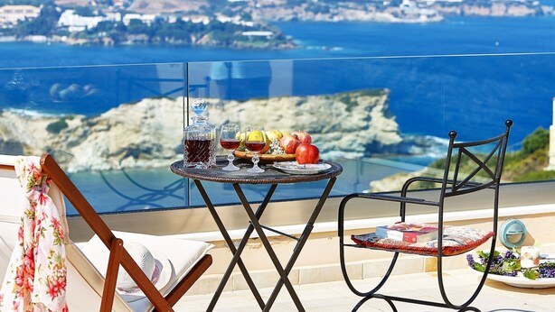 Een balkon met een eettafel, een stoel en uitzicht op de kustlijn.