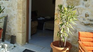 A stone building with a doorway leading to an interior space, a potted plant, and a wooden chair. - Studio "Marina" in Sivas Traditional Village. (Sivas)