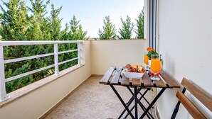A balcony with a table set for breakfast, a bench, and a view of trees. - "Malena" Nature and Sea View House (Sidonia)