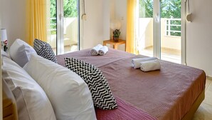 A bedroom with a bed, curtains, a nightstand, and a view through a sliding door. - "Malena" Nature and Sea View House (Sidonia)