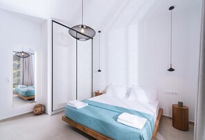 Ein modernes Schlafzimmer mit Bett, Spiegel und Pendelleuchten.