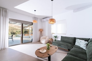 Ein modernes Wohnzimmer mit einer Couch, einem Couchtisch und Blick auf einen Pool und Außenbereich.