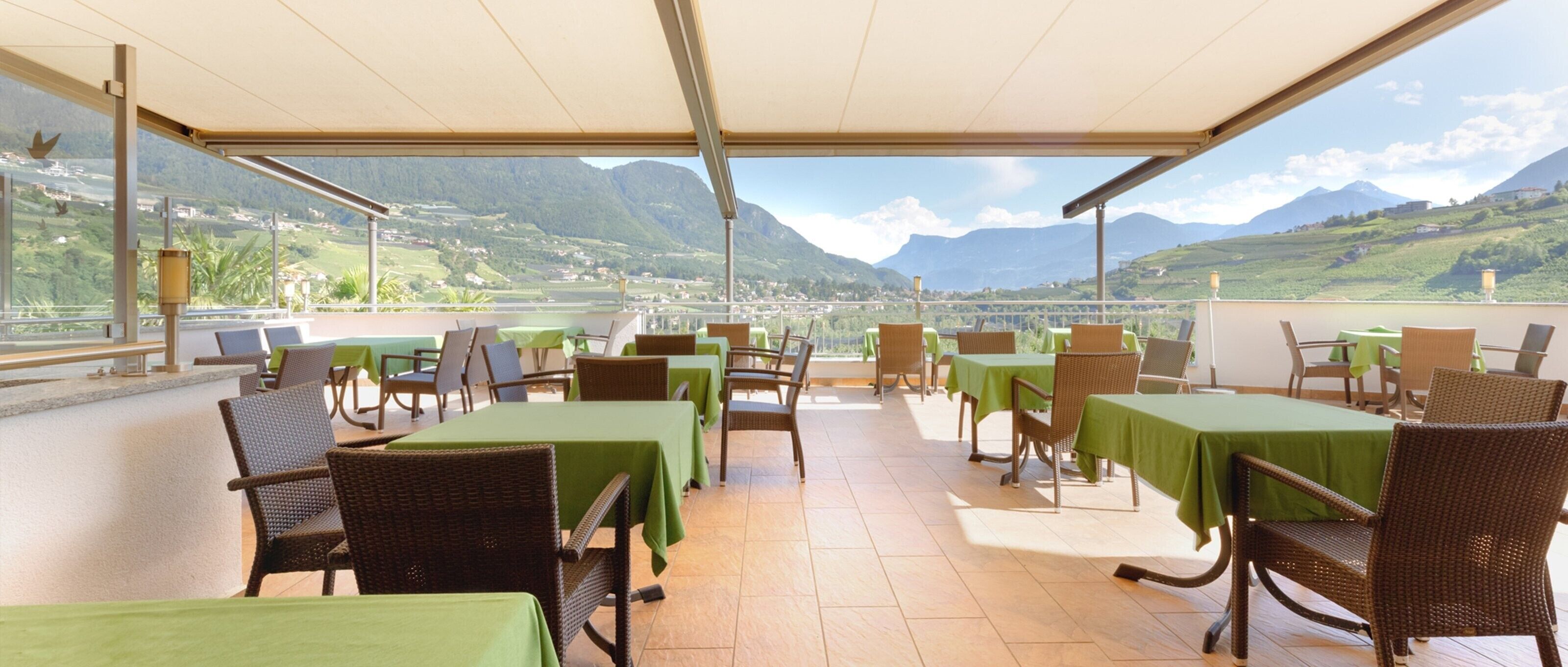 A terrace with tables and chairs, overlooking a mountainous landscape.