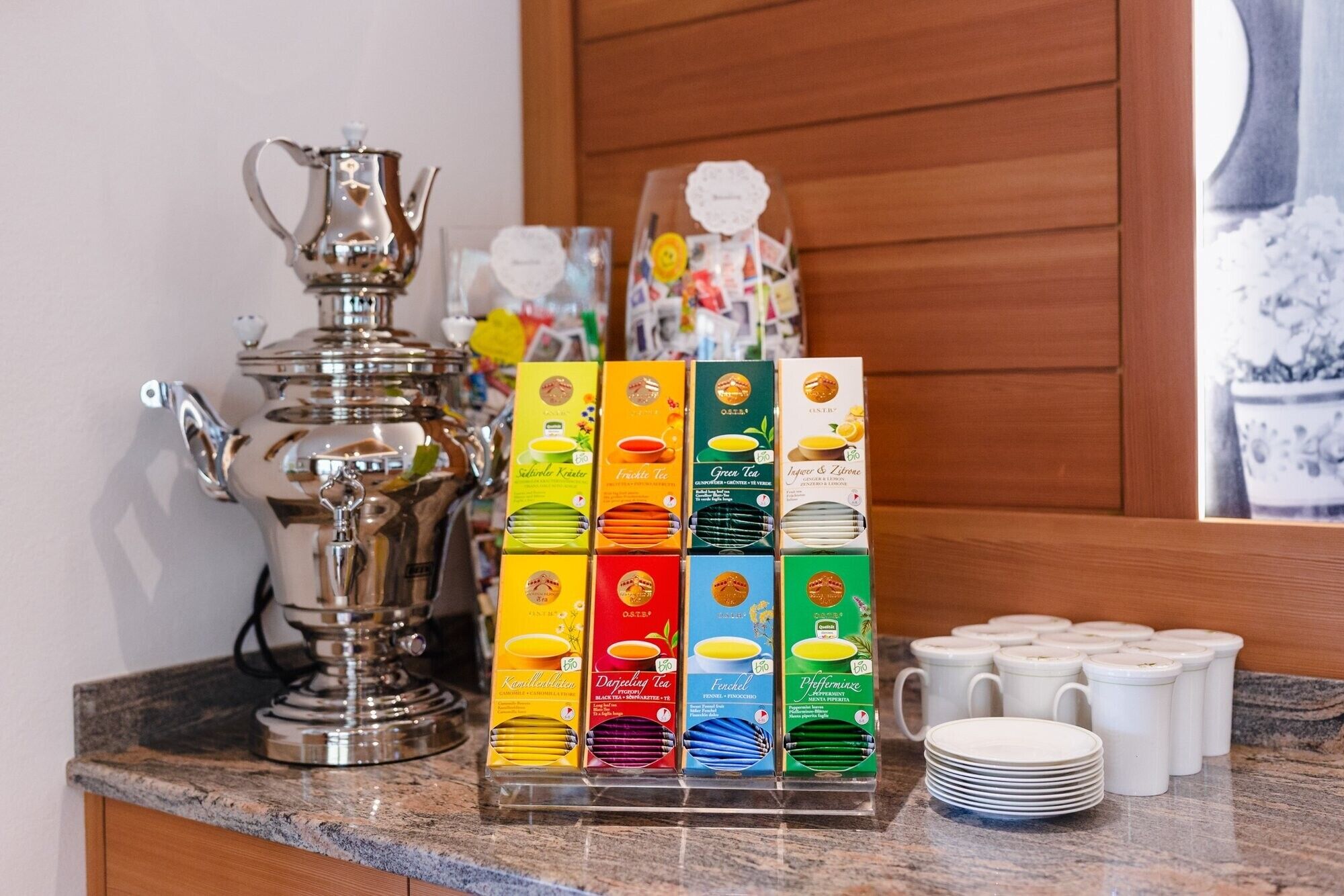 Un comptoir de cuisine aménagé en coin thé, avec différentes boîtes de thé et une théière.