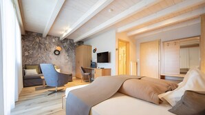 Ett modernt sovrum med en säng, ett skrivbord, en stol och en tv.