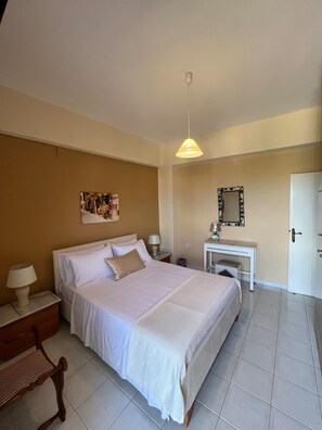 A bedroom with a bed, bedside tables, a desk, a chair, a hanging light fixture, a mirror, and a door. - Marina's traditional house at Sivas village (Sivas)
