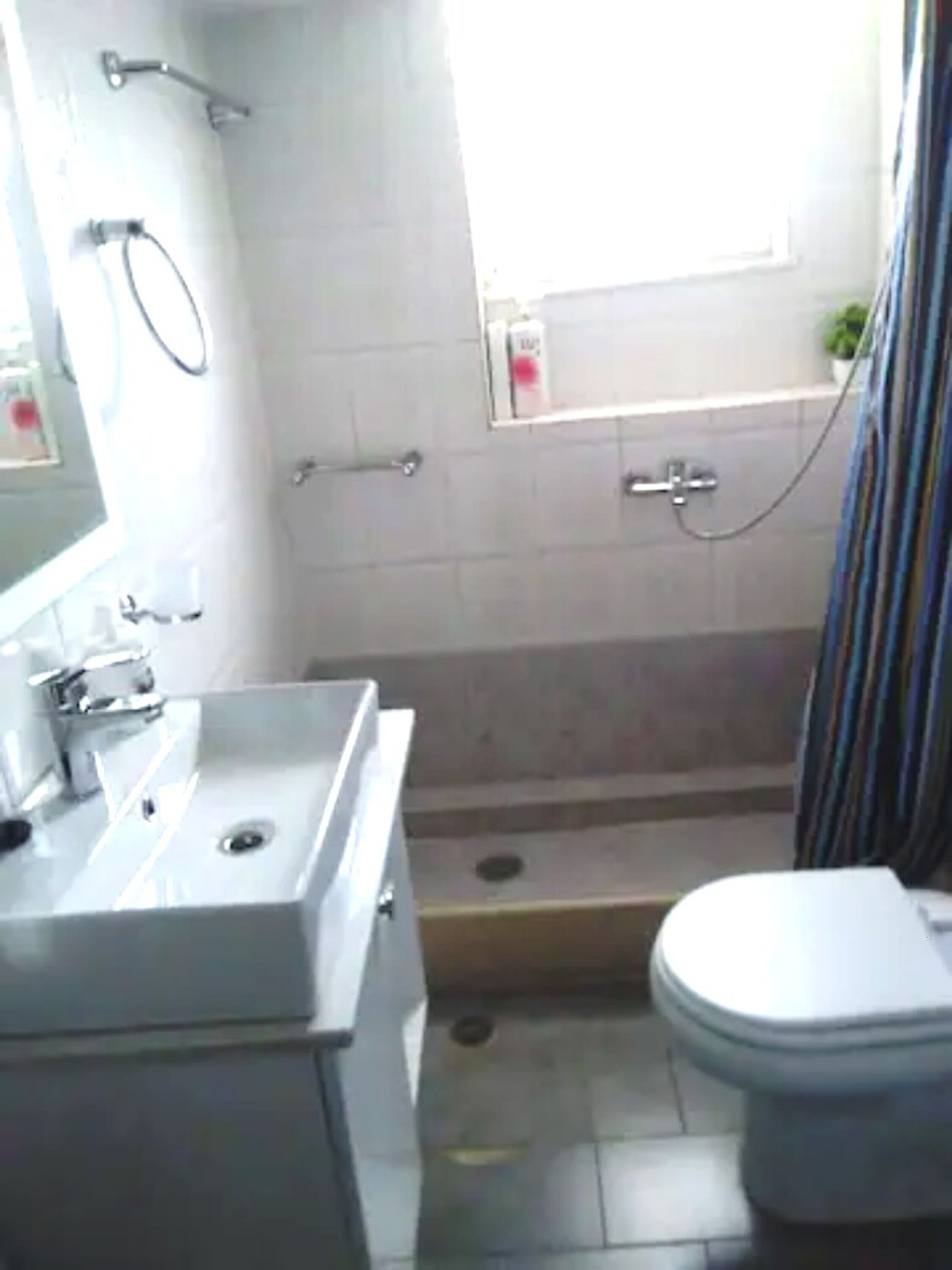 Une salle de bain équipée de toilettes, d’un lavabo, d’une douche et d’une fenêtre.