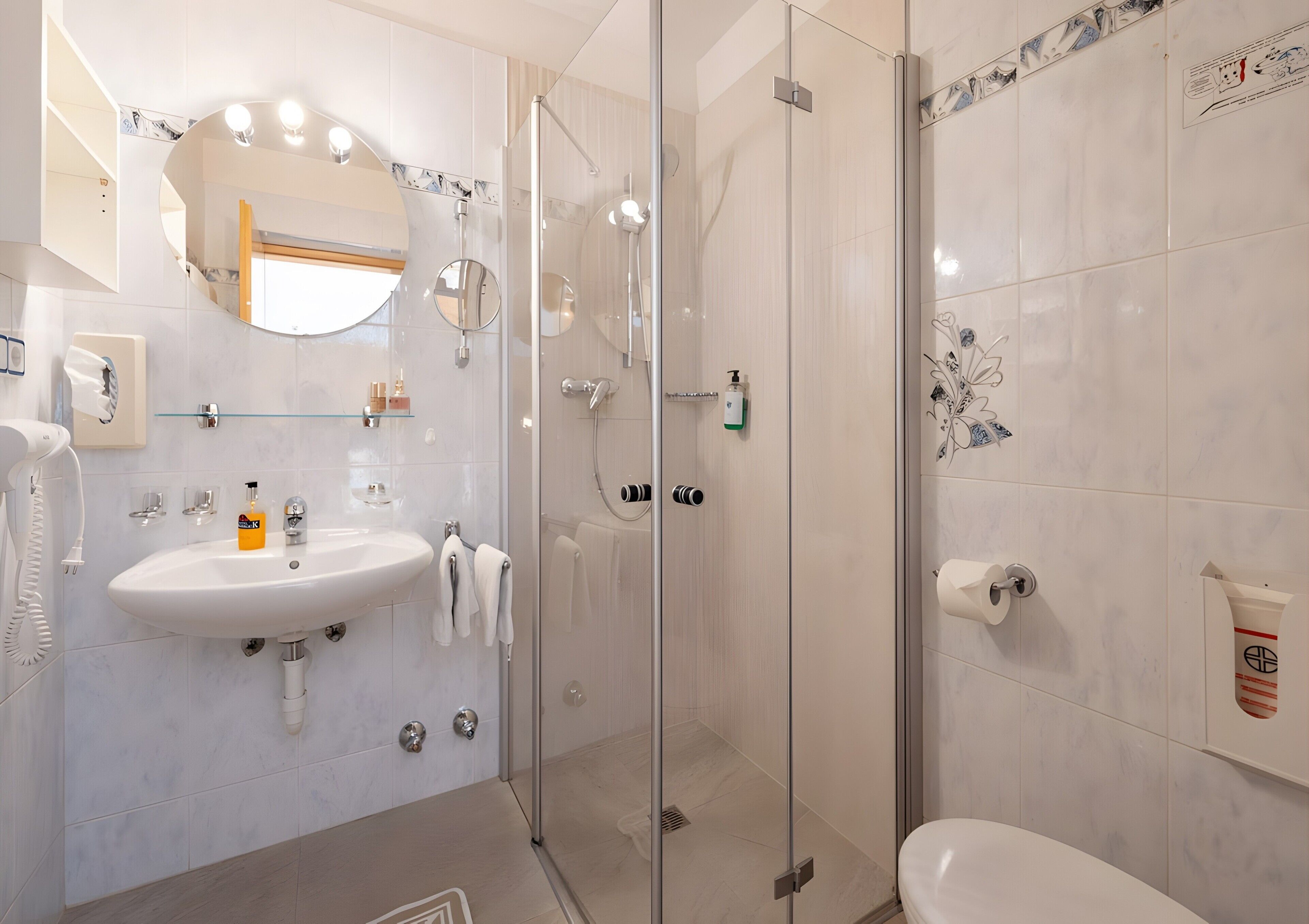 A modern bathroom with a glass-enclosed shower, a sink with a mirror, and a toilet.
