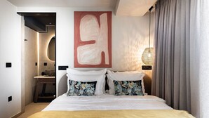 Quarto de hotel moderno com uma cama grande, um quadro abstrato pendurado na parede, um abajur e vista para a paisagem urbana pela janela.
