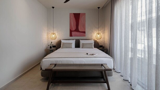 Ein modernes Schlafzimmer mit einem Bett, Nachttischen, einem Deckenventilator und einem großen Fenster mit transparenten Vorhängen.