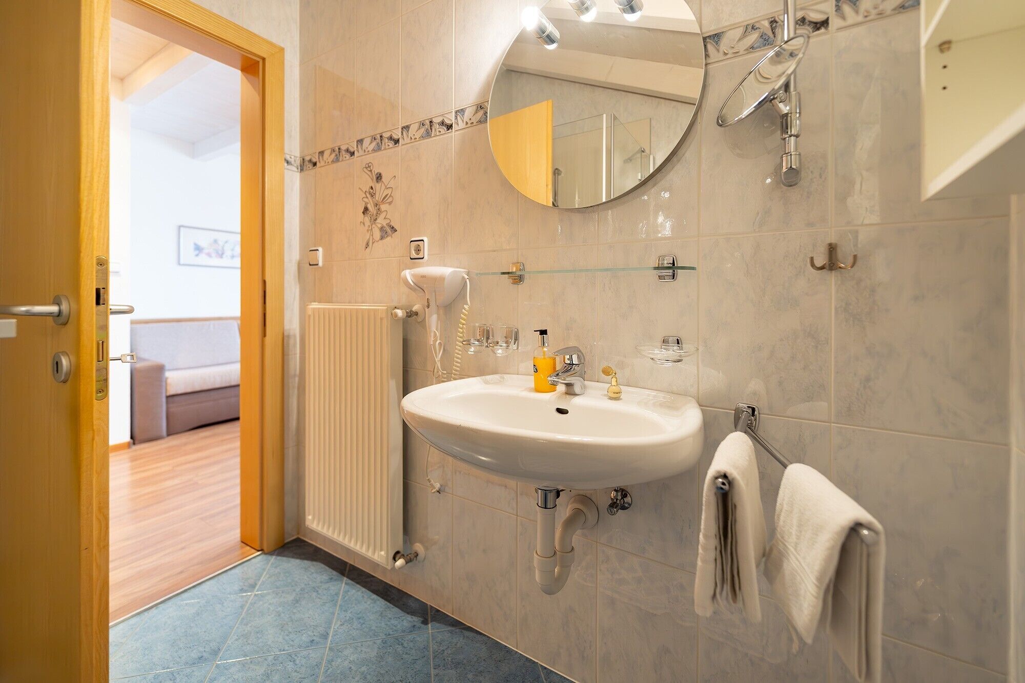 A bathroom with a sink, mirror, towel rack, and a radiator.