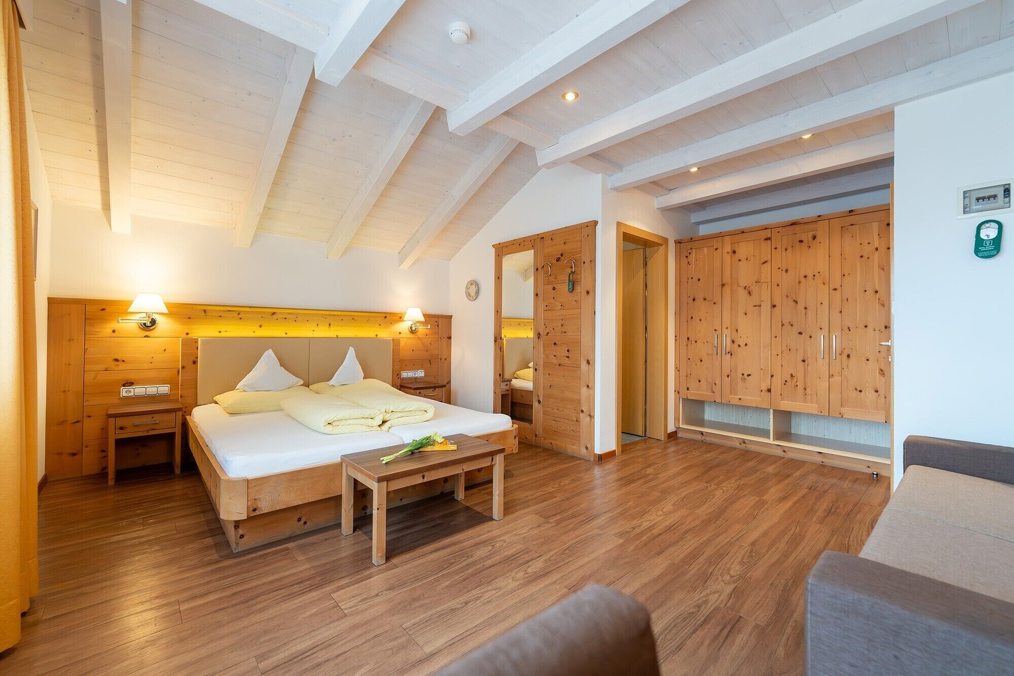 Ein Schlafzimmer mit einem hölzernen Bett, Nachttischen, einer Bank und einem Kleiderschrank.
