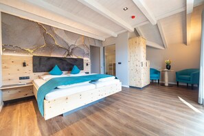 A modern bedroom with a wooden bed, a headboard with abstract art, a wooden wardrobe, and a view of the outside. - Room 'Passerblick Suite 2' with Mountain View, Wi-Fi and Air Conditioning (Tirolo)