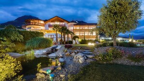 A multi-story hotel with a pool, surrounded by landscaped gardens and a mountain backdrop. - Room 'Passerblick Suite 4' with Mountain View, Wi-Fi and Air Conditioning (Tirolo)