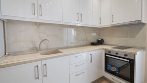 Una cocina moderna con armarios blancos, un fregadero, una estufa y una cafetera.