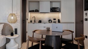 Una cocina compacta con microondas, hervidor y cafetera, una laptop sobre la mesa, y una lámpara colgante.