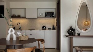 A modern kitchen with white cabinets, a microwave, and a dining area with a round table and chairs.