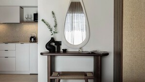 A modern kitchen with white cabinets, a wooden console table, a mirror, and a vase with greenery.
