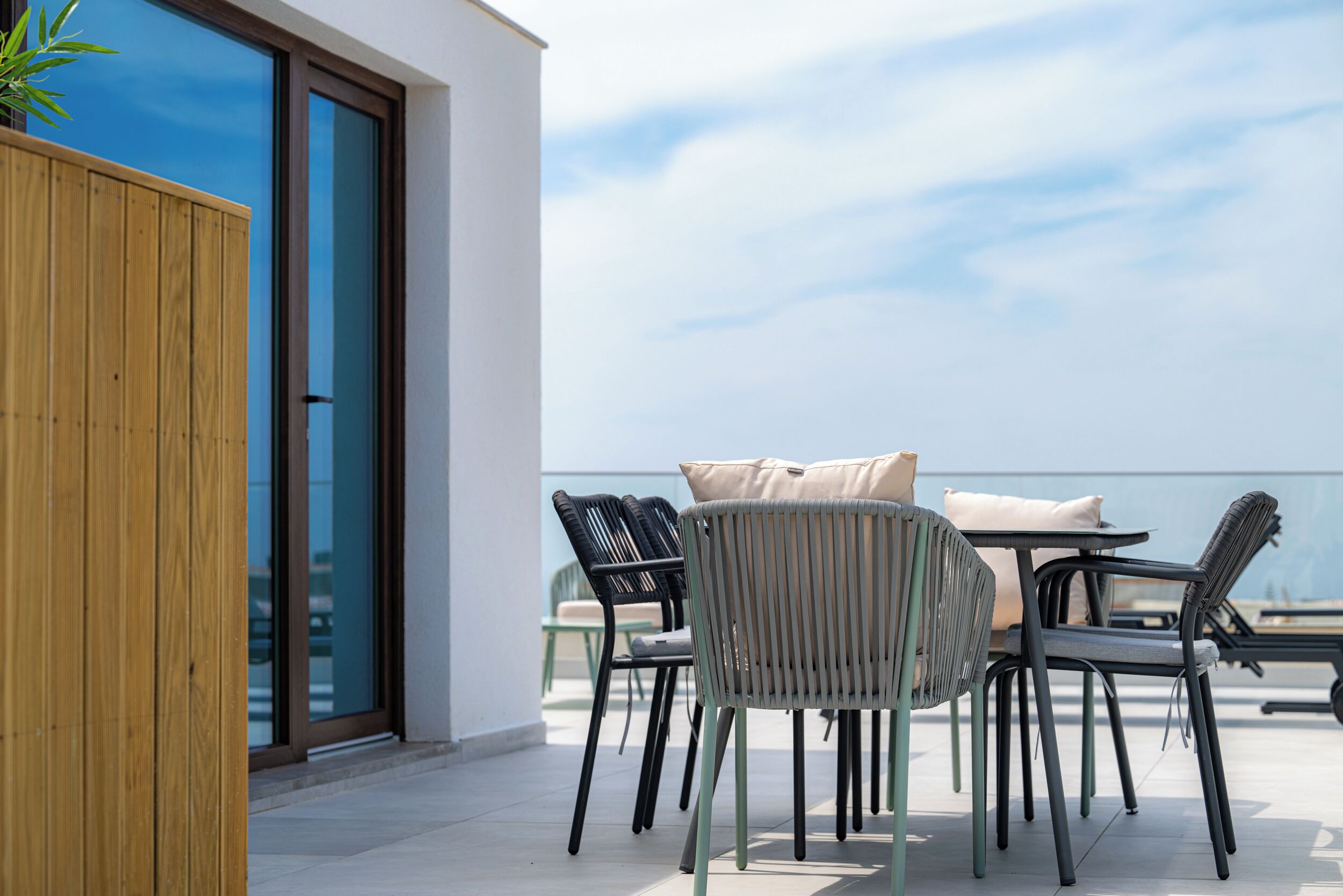 Un espace extérieur aménagé avec des chaises et une table, une clôture en bois et une porte vitrée donnant sur un balcon.