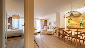 Ett modernt hotellrum med en säng, ett sängbord, en lampa och utsikt över vardagsrummet.
