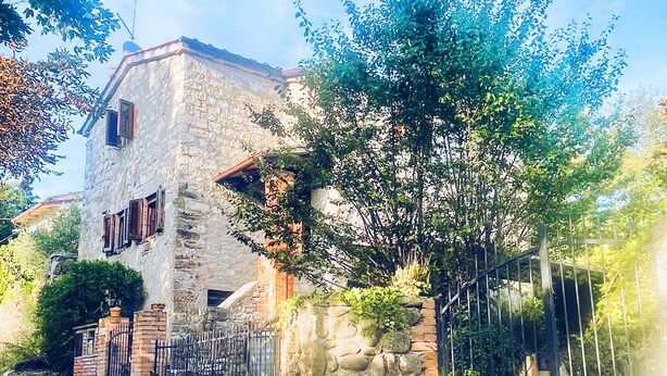 A stone building with a rustic appearance, a gated entrance, and a tree in the foreground. - Hidden Tuscan Gem- surrounded by rolling hills. Charming villa, sleeps up to 6. (Caprese Michelangelo)