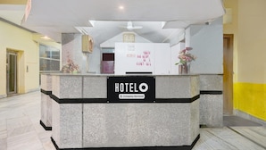 Una recepción de hotel con un cartel que dice 'HOTELO', un reloj y un florero.