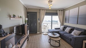 Ett modernt vardagsrum med en soffa, ett soffbord, en tv och en balkong med utsikt.