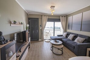 A modern living room with a sofa, coffee table, TV, and a balcony with a view.