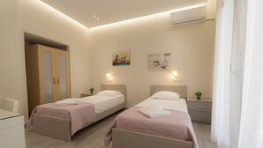 Een hotelkamer met twee bedden, een bureau, een kledingkast en een airconditioning.