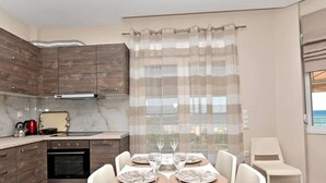 Een moderne keuken met houten kastjes, een inbouwoven en een eethoek met een tafel gedekt voor vier personen.