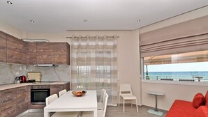 Een moderne keuken met een eethoek, een rode bank en uitzicht op zee.