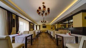 Un comedor de hotel con varias mesas, sillas, candelabros y una zona de bar.
