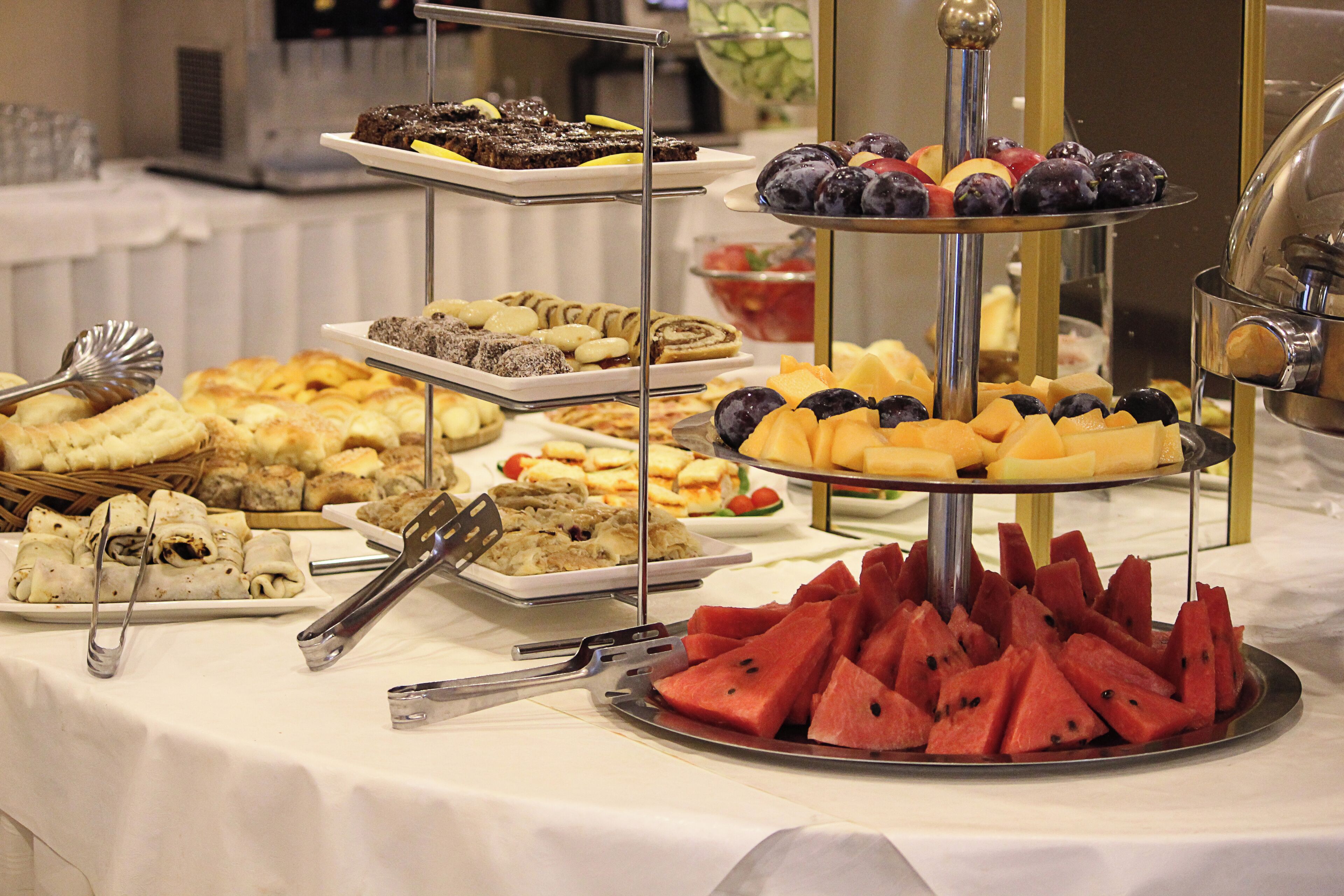 A buffet with various food items including pastries, fruits, and desserts.