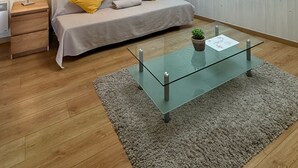 A modern bedroom with a skylight, a glass coffee table, a sofa with yellow cushions, a bedside lamp, and a patterned wall. - Matsya Hostel (Anglet)