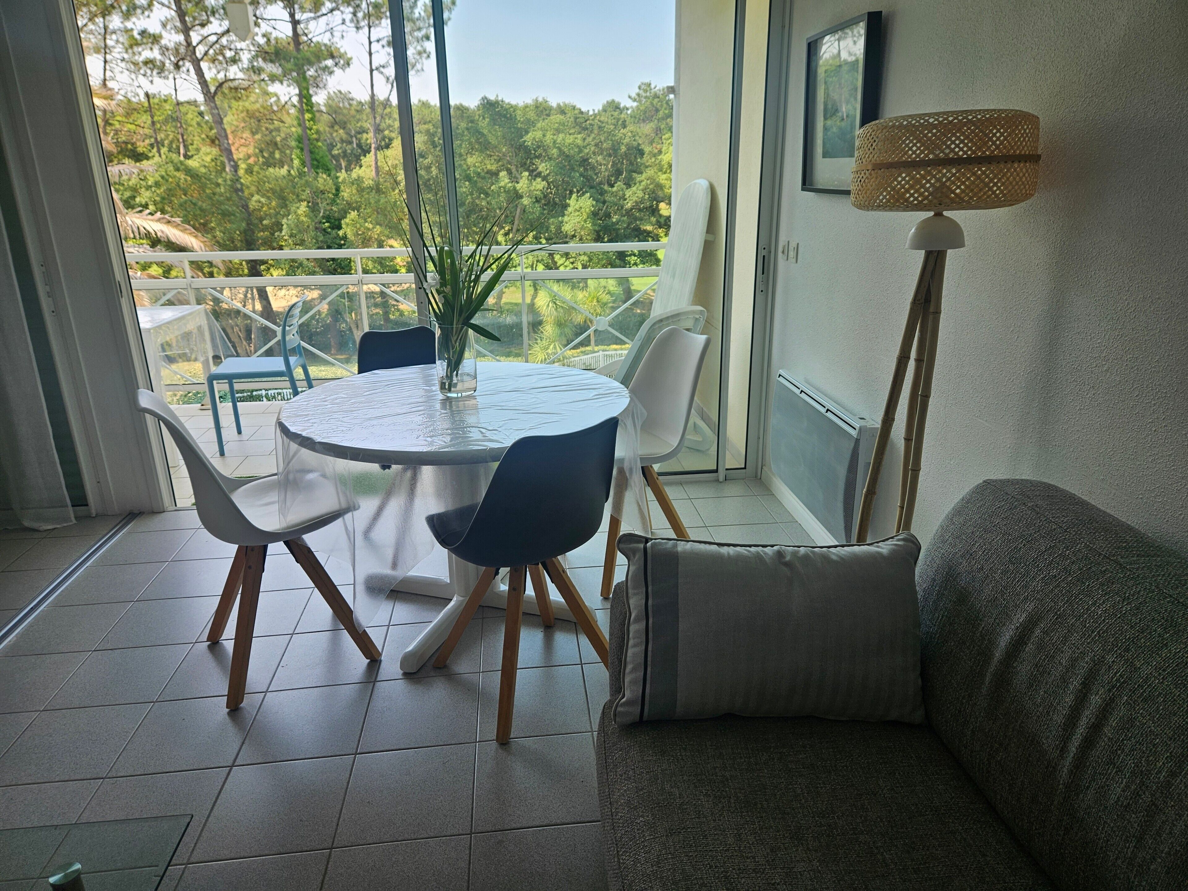 Un balcone con tavolo, sedie, lampada da terra e divano.