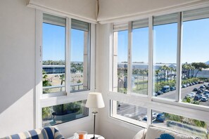 A room with large windows, a lamp, a view of a parking lot, and a building in the background. - Anacasa Albatros MET Oliva Nova Golf AT469 (Oliva)