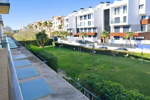 Una zona residencial con edificios de apartamentos modernos, un césped cuidado y un cielo despejado.
