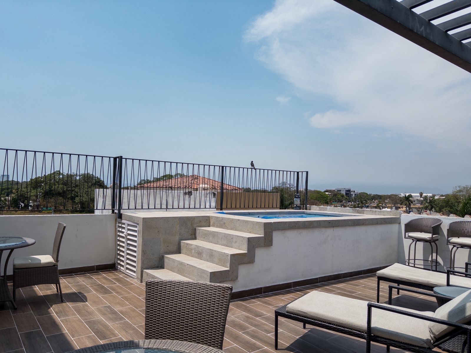 Eine Außenpatio mit Whirlpool, Korbmöbeln und Blick auf die Stadtlandschaft.