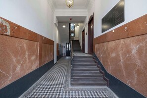 A marble-floored hallway with a staircase, a chandelier, and a plaque on the wall. - Spacious Studio in Krakow | Close to Wawel Castle | A Place to Work (Kraków)
