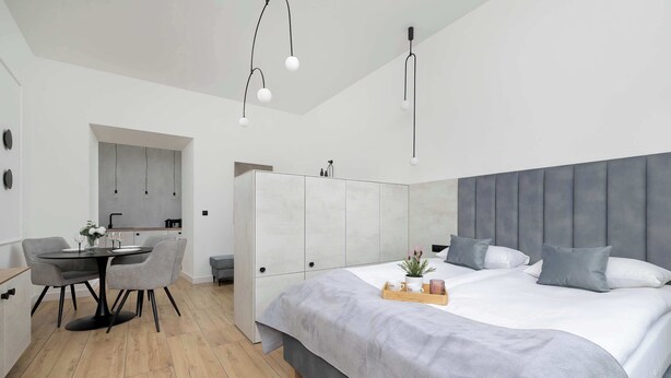 Un dormitorio moderno con una cama grande, un rincón de comedor con mesa y sillas, y una kitchenette.