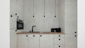 Una cocina moderna con horno empotrado, un lavabo y una cafetera.