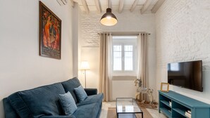 Una sala de estar con un sofá, un televisor, una lámpara y una ventana.