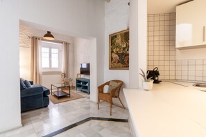 Ein Wohnzimmer mit einer Couch, einem Couchtisch, einem Fernseher und einem Gemälde an der Wand.